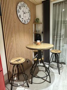 a table with two stools and a clock on a wall at Le Refuge in Margencel