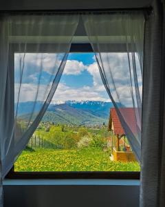 a window with a view of a house and mountains at Ammon Mountain Villas in Bran