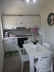 a kitchen with a white table with a vase of flowers on it at Esmeralda B&B in Casa San Biagio