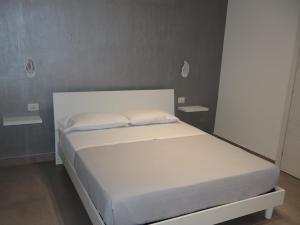 a white bed in a bedroom with two shelves at Esmeralda B&B in Casa San Biagio