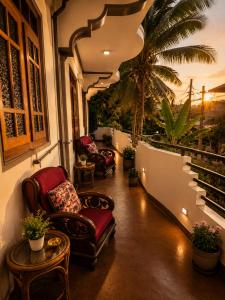 a balcony with chairs and a table and a palm tree at Cleopatra Rest House in Nilaveli