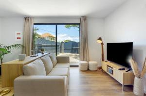 a living room with a white couch and a tv at Modern Sea View Studio with Private Parking in Gaula