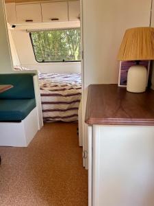 a room with a bed and a table and a lamp at La caravane dans le verger in Saint-Erblon