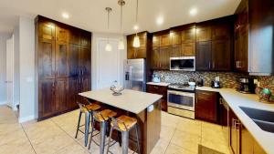 a kitchen with wooden cabinets and a island with bar stools at Entrada at Moab #668 in Moab +49 photos