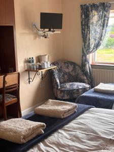 a room with two beds and a chair and a tv at Corrib View Villa - Guest Accomodation in Cong