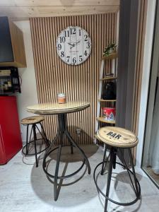 a table and two stools with a clock on a wall at Le Refuge in Margencel