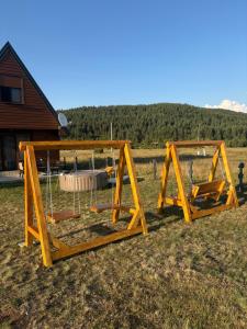 a swing set in a field with a house at Zabljak villa VAM in Žabljak