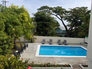 a swimming pool in a yard with chairs and trees at Pearls and Palms Inn in Negril