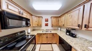 a kitchen with wooden cabinets and a sink and a stove at Red Cliff Condos #1B in Moab