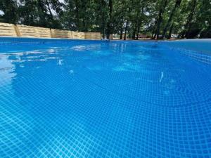 a large blue swimming pool with trees in the background at Camping Paus'Art Déco in Villemer
