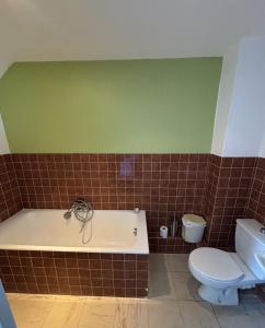 a bathroom with a bath tub and a toilet at Hôtel de la poste in Saint-Valery-en-Caux +2 photos