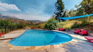 a swimming pool in a backyard with red chairs and a bluearp at Pack Creek ~ Trails End in Spanish Valley