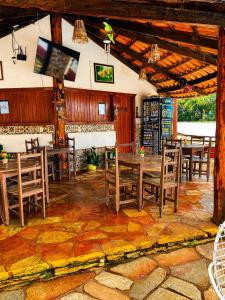 a dining room with tables and chairs and a flat screen tv at Pousada Recanto da Serrinha in Corumbá de Goiás