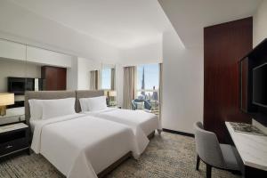 a hotel room with a large white bed and a desk at Dusit Thani Dubai in Dubai