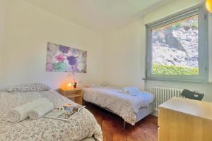 a bedroom with two beds and a window at Gaeta 'Lake View' in San Siro +7 photos