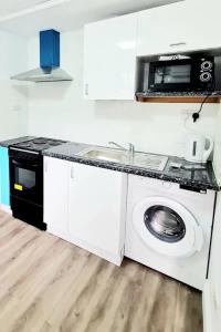 a kitchen with a washing machine and a sink at Comfortable 2 Bed Apartment- Pass the Keys in Basildon +11 photos