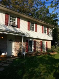 a white house with red shuttered windows and a yard at The Haven at Charity House in Waldorf