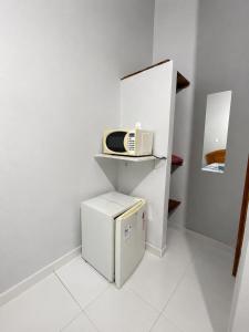 a small white kitchen with a microwave and a refrigerator at Pousada Recanto da Serrinha in Corumbá de Goiás