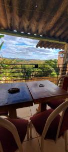 a wooden table and chairs on a balcony with a view at Contos de Alice in Tiradentes