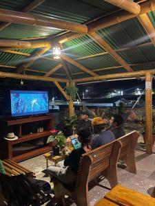 a group of people sitting on a bench watching tv at GoldenBird Mindo in Mindo