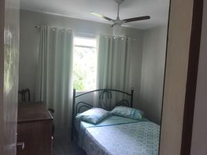 una camera con letto, ventilatore a soffitto e finestra di Casas de Temporada Conservatória a Conservatória