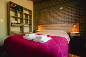 a bedroom with a pink bed with towels on it at Entre Campos in Los Reartes