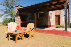 two chairs and a table in front of a house at Entre Campos in Los Reartes