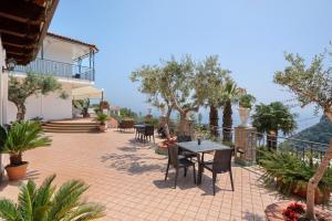 a patio with a table and chairs and trees at Villa Azzurra in Massa Lubrense