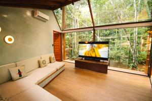 a living room with a large window and a flat screen tv at Cirandeira Amazon World EcoResort in Manacapuru