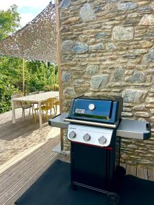 a grill on a deck with a table and a stone wall at Pleta Moragas in Osséja