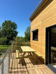 a picnic table on a deck next to a building at Le chalet des Marais in Saint-Molf