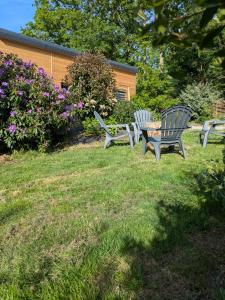 three benches sitting in the grass in a yard at Le chalet des Marais in Saint-Molf