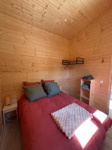 a bedroom with a red bed in a wooden room at Le chalet des Marais in Saint-Molf