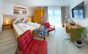 a living room with a white couch and red chairs at Hotel Ascona Bad Krozingen Frisch renoviert in bester Lage, nahe Autobahn, Kurpark und Vita Classica in Bad Krozingen