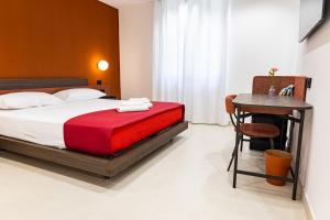 a bedroom with a bed with a red blanket and a table at Villa delle Rose Pompei Rooms and Suite in Pompei