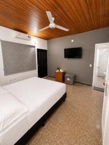 a bedroom with a white bed and a ceiling fan at Hotel Luna Del Rio in Puerto Salgar
