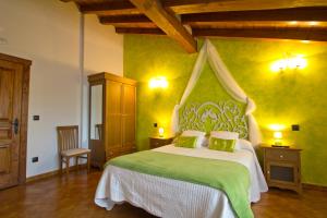 a bedroom with a large bed with green walls at Posada La Fabula in Santillana del Mar
