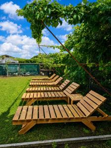 a group of wooden benches sitting in the grass at Casa KariAna in Murighiol