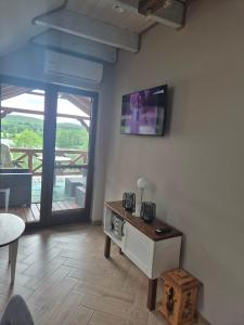 a living room with a table and a tv on the wall at Dom za wydmą in Nielbark