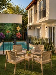 three chairs and a table in front of a pool at Complejo GOOD LIFE in Miramar