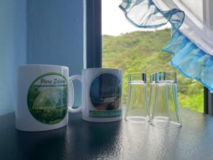 two coffee mugs and two glasses sitting on a table at Ecoesferas Glamping in La Ese