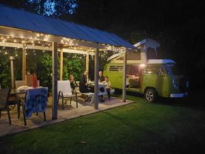 a group of people sitting at a table next to a van at Te Mata Lodge in Tapu