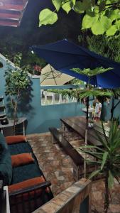a patio with benches and a blue umbrella at Mini-villa ajdir in Ajdir
