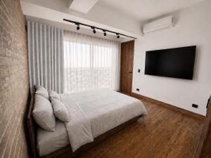 a bedroom with a bed and a flat screen tv at Altitud Medellín Viem Living in Medellín