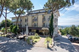 a building with tables and chairs and trees at Albergo Centopini in Gemmano