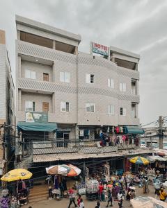 a large building with people walking in front of it at Hôtel Merveille Lomé in Lomé