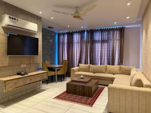 a living room with a couch and a flat screen tv at The Horizon Hotel Islamabad in Islamabad