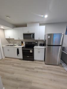a kitchen with white cabinets and a stainless steel refrigerator at Olas Place in Regina