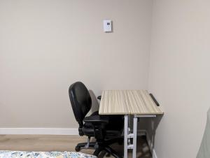 an office desk with a black chair and a table at Olas Place in Regina