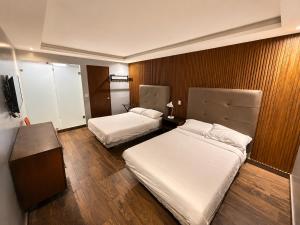 a hotel room with two beds and a television at hotel 202 in Monterrey